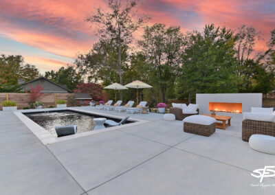 sunset view of a luxurious pool and patio with white furniture