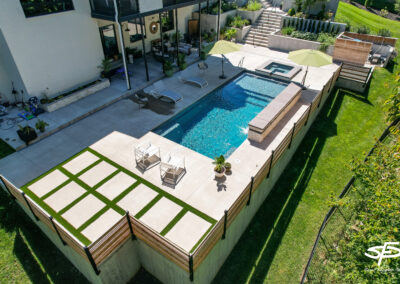 aerial view of a modern stylish pool with hardscaping and artificial turf