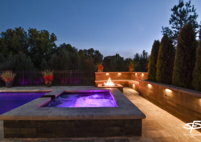 hot tub and fire pit with hardscaping and lighting
